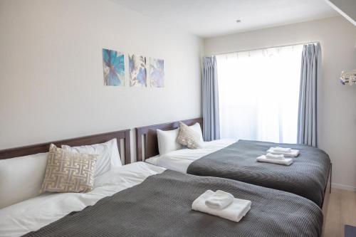 two beds in a hotel room with towels on them at D-house in Osaka
