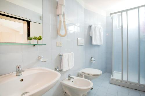 a white bathroom with a sink and a toilet at Hotel Universal in Riccione