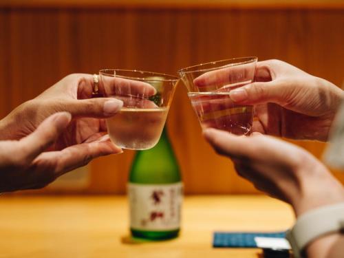 two people holding glasses of wine next to a bottle at RITA Yame Fukushima in Yame