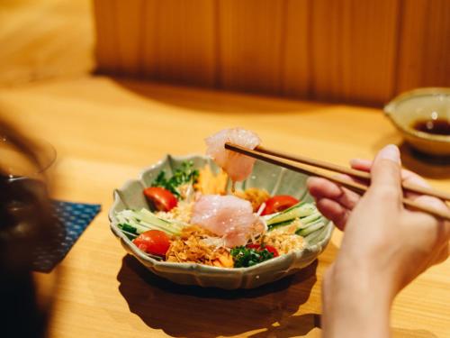 a person is holding a bowl of food with chopsticks at RITA Yame Fukushima in Yame