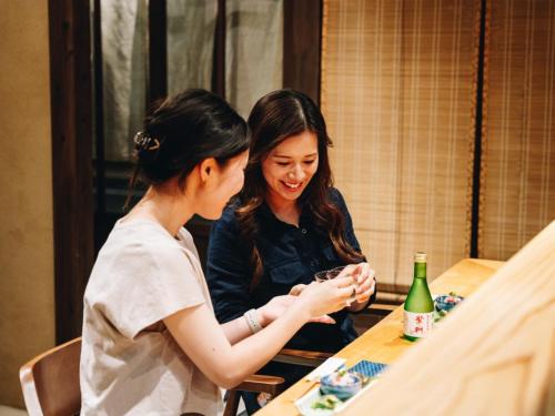 two women sitting at a table looking at a cell phone at RITA Yame Fukushima in Yame