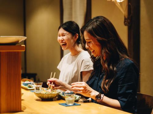 two women sitting at a table eating food with chopsticks at RITA Yame Fukushima in Yame