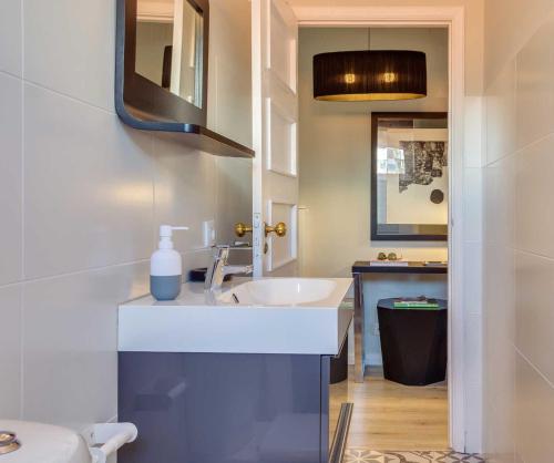 uma casa de banho com um lavatório e um espelho em Baixa24 - Bolhão Apt with Sunset Rooftop no Porto