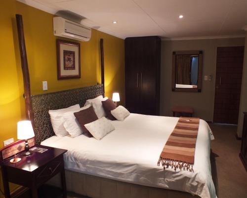 Un dormitorio con una gran cama blanca en una habitación. en Acacia Guest House, en Nelspruit