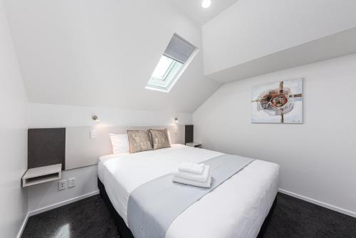 a bedroom with a large white bed with a skylight at 315 Motel Riccarton in Christchurch