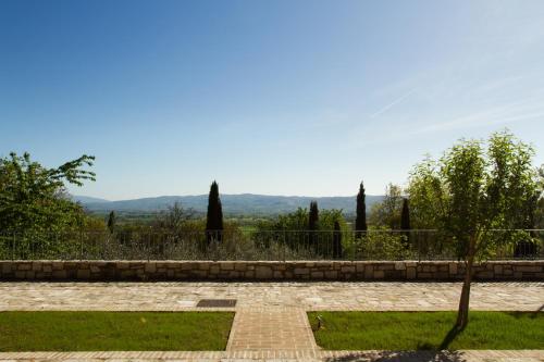 a garden with a brick path and trees and a fence at Villa Degli Ulivi in Assisi