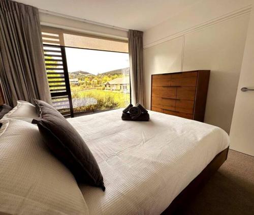 Un dormitorio con una cama grande con una ventana grande. en Cosy Wanaka Townhouse, en Wanaka