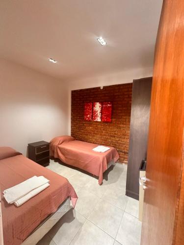 a room with two beds and a brick wall at Kaizen Apart in Caleta Olivia