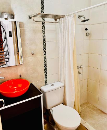 a bathroom with a white toilet and a red sink at Kaizen Apart in Caleta Olivia