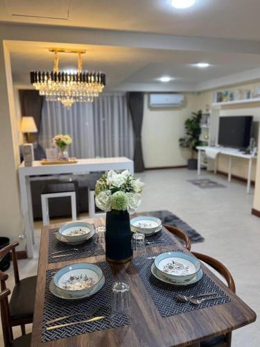 a wooden table with plates and flowers in a living room at 10MIN 曼谷独栋Chatuchack,Kasetsart精品别墅 MYSTORY HOUSE in Bangkok