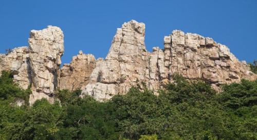 a rocky mountain with trees in front of a blue sky at Bangsaen Villa Hotel in Si Racha