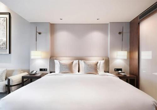 a bedroom with a large white bed with two tables at 上海松江广富林宰相府酒店 in Songjiang