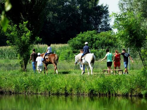 a group of people riding horses near a body of water at Agriturismo Adriano Pedretti in Badia Polesine