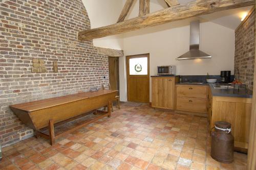 uma cozinha com um banco de madeira numa parede de tijolos em Vakantiewoning Venderhof em Maaseik