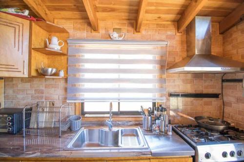 a kitchen with a sink and a stove and a window at Arriendo Cabaña Cutipay Valdivia in Valdivia