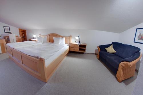 a bedroom with a large bed and a blue couch at Ferienhotel Starennest in Schindelberg