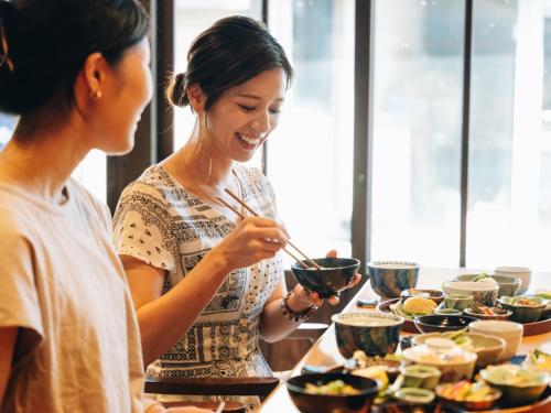 two women standing at a table eating food with chopsticks at RITA Yame Fukushima in Yame