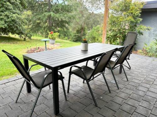 WarrandyteSpacious 4 bed, 2 lounge, 2 bath, Acre home with tree top views - Yarra Valley Gateway!的露台上的木桌和椅子