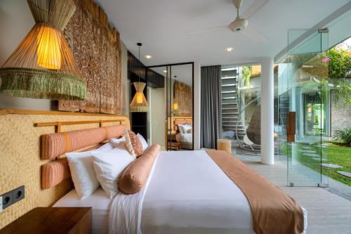 a bedroom with a bed and a glass wall at Villa Toraja in Canggu