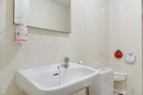 a white bathroom with a sink and a toilet at Good Deal and Cozy 2BR Apartment M-Town Residence near Mall By Travelio in Tangerang