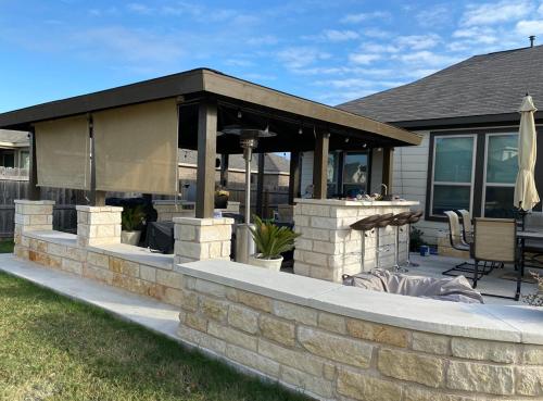 a patio with a stone wall and an outdoor grill at Toscana Villa in Round Rock