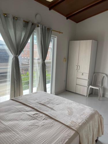 a bedroom with a bed and a large window at Apartamento Villa Alba in Arboletes
