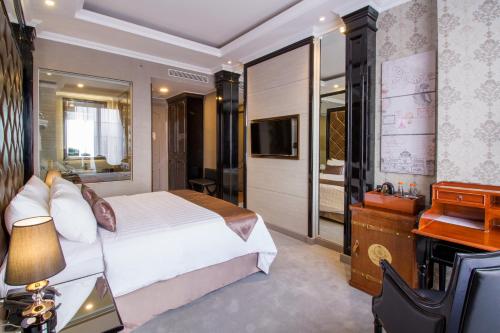 a bedroom with a bed and a desk and a television at d'Primahotel Bandung in Bandung