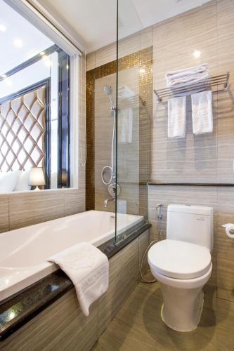 a bathroom with a toilet and a tub and a sink at d'Primahotel Bandung in Bandung