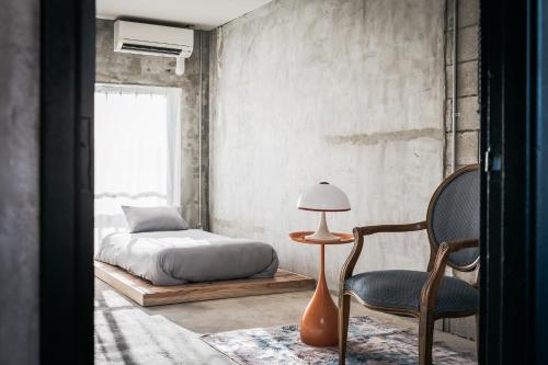 a bedroom with a bed and a chair and a lamp at Yanbaru Hostel in Kunigami