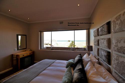 um quarto com uma cama grande e uma janela grande em Westward HO Apartment 13 em Cidade do Cabo