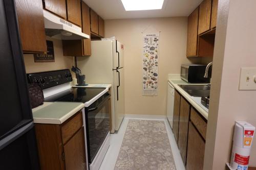 eine kleine Küche mit Holzschränken und einem Kühlschrank in der Unterkunft Entire 1 BR Condo- Near Anschutz, UC Health, DIA- In-Unit Washer Dryer- Seasonal Discounts! in Aurora