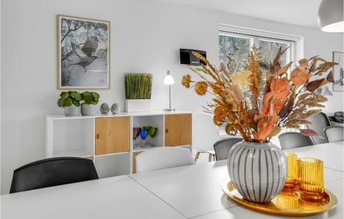 a white dining room with a vase of flowers on a table at Awesome Home In Blåvand With Sauna in Blåvand