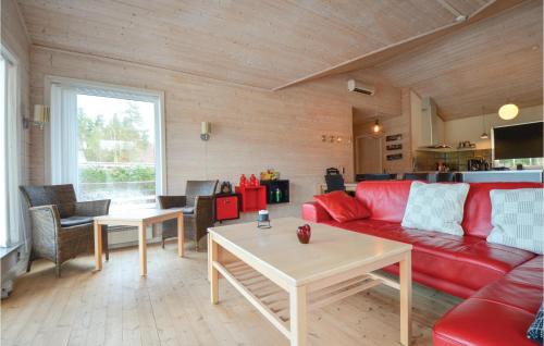 a living room with a red couch and a table at Holiday Home Kærsangervej Ebeltoft in Øksenmølle