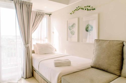 a bedroom with a bed with white sheets and a window at Simple and Cozy Living Studio Room at Poris 88 Apartment By Travelio in Tangerang