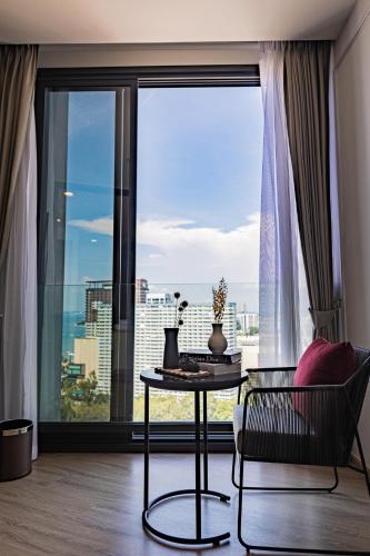 a living room with a table and a large window at Luxury Condo Edge Central Pattaya in Pattaya