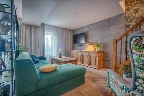 a living room with a green couch and a kitchen at Hotel Kotarz Spa&Wellness in Brenna