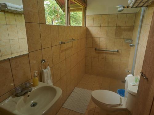 a bathroom with a shower and a sink and a toilet at Santa Maria Volcano Lodge Hotel & Restaurante in Hacienda Santa María