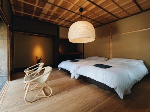 two beds in a room with two chairs and a chandelier at RITA Yame Fukushima in Yame