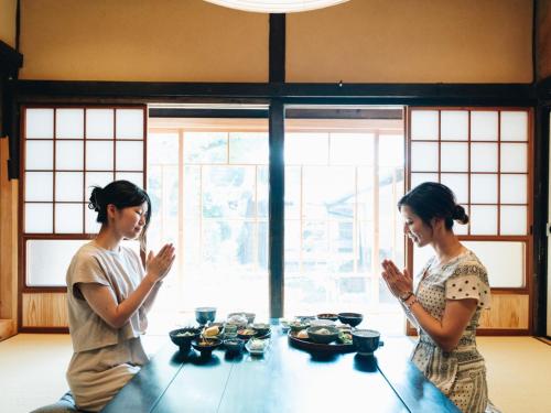 two women are sitting at a table praying at RITA Yame Fukushima in Yame