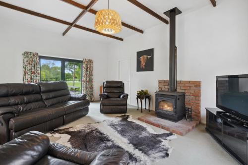 a living room with a leather couch and a fireplace at Clarendon Estate - Masterton Holiday Home in Masterton