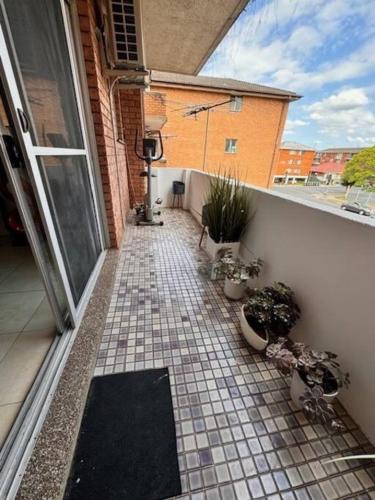 a balcony with a tiled floor with potted plants at Alison's central apartment in Cabramatta