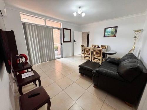 a living room with a black leather couch and a table at Alison's central apartment in Cabramatta