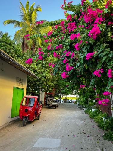 a red car parked next to a building with pink flowers at Thundi Village & Spa in Maalhos