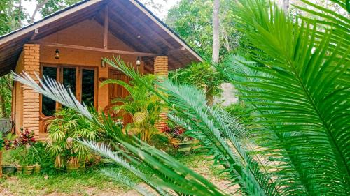 a wooden house with palm trees in front of it at Lotus Eco Villa in Sigiriya