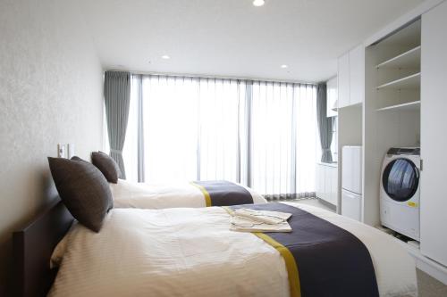 a hotel room with two beds and a tv at 3 Wellness in Okayama