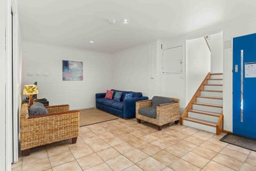a living room with a blue couch and a staircase at Karalee by Experience Jervis Bay in Vincentia