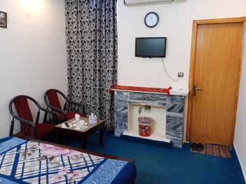 a living room with a fireplace and a tv at New Orion Lodge in Islamabad