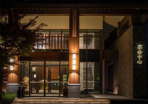 a building with large glass doors with a lit up front at 上海松江广富林宰相府酒店 in Songjiang