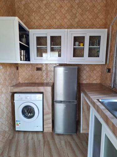 a kitchen with a refrigerator and a washing machine at Bethel Apartment in Oyarifa