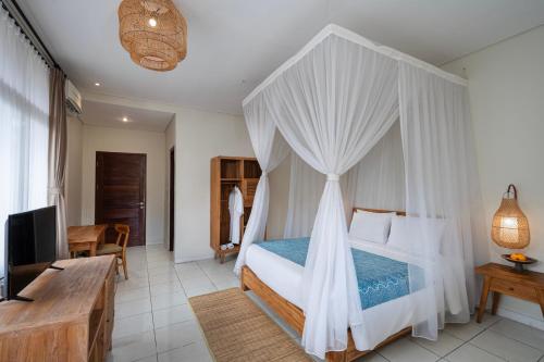 a bedroom with a canopy bed and a living room at Pertiwi Resort & Spa in Ubud